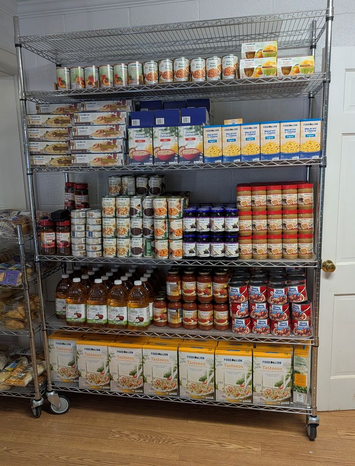 CRS pantry shelving stocked with canned vegetables, oatmeal, macaroni and cheese, peanut butter, apple juice and pasta sides